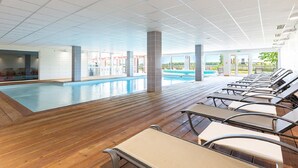 Une piscine dotée de chaises longues, d’une terrasse en bois et offrant une vue sur l’extérieur.