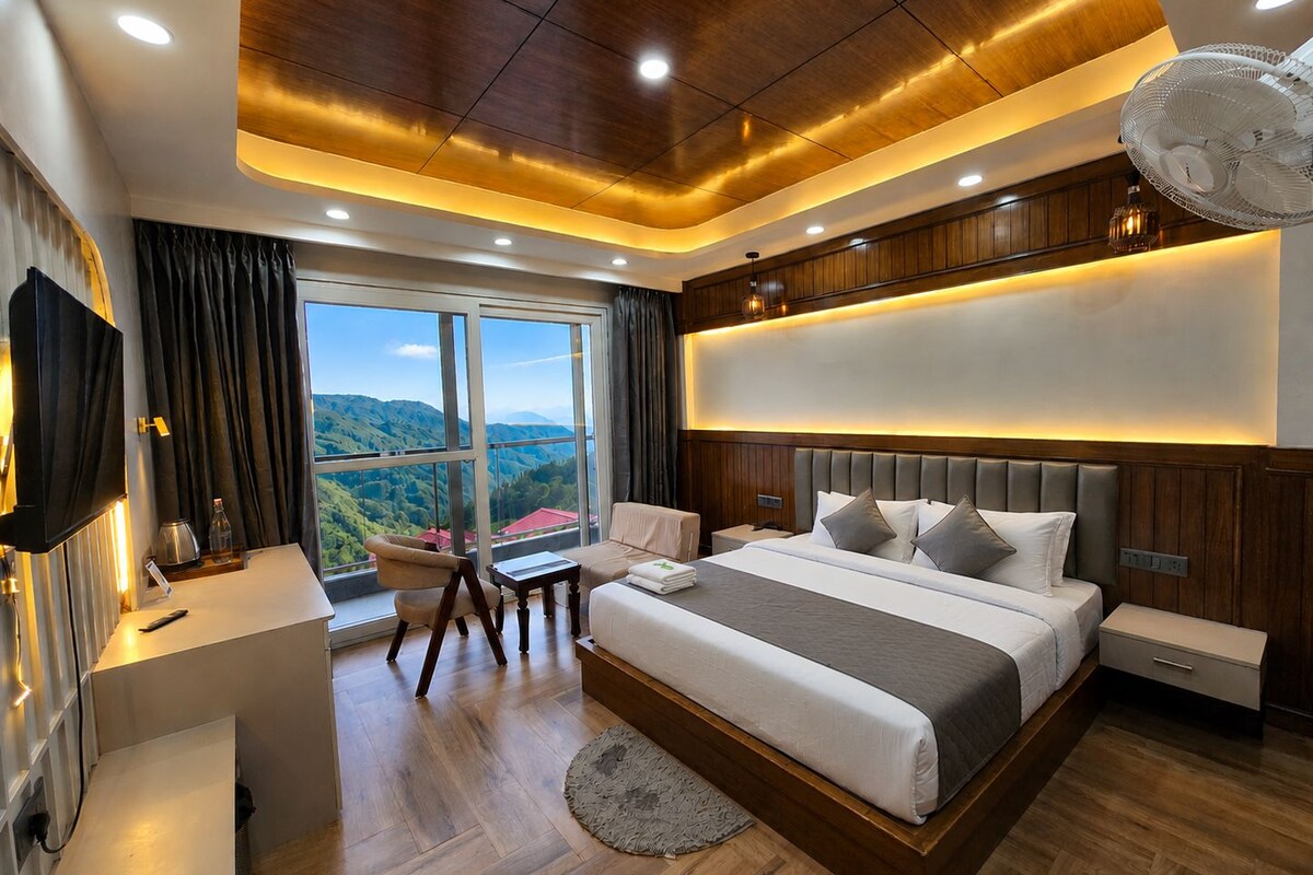 A modern bedroom with a large bed, a desk, and a view of a mountainous landscape.