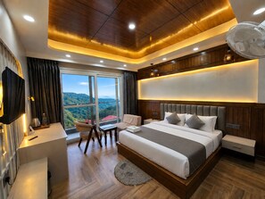 A modern bedroom with a large bed, a desk, and a view of a mountainous landscape. - The Heaven Paradise Premium (Shimla)