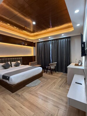 A modern hotel room with a large bed, a desk, a chair, and a television. - The Heaven Paradise Premium (Shimla)