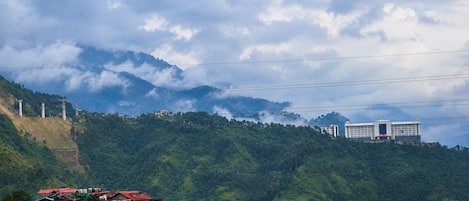A mountainous landscape with residential buildings and a large white building in the distance.