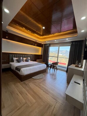A modern bedroom with a large bed, a desk, and a view of the mountains. - The Heaven Paradise Premium (Shimla)