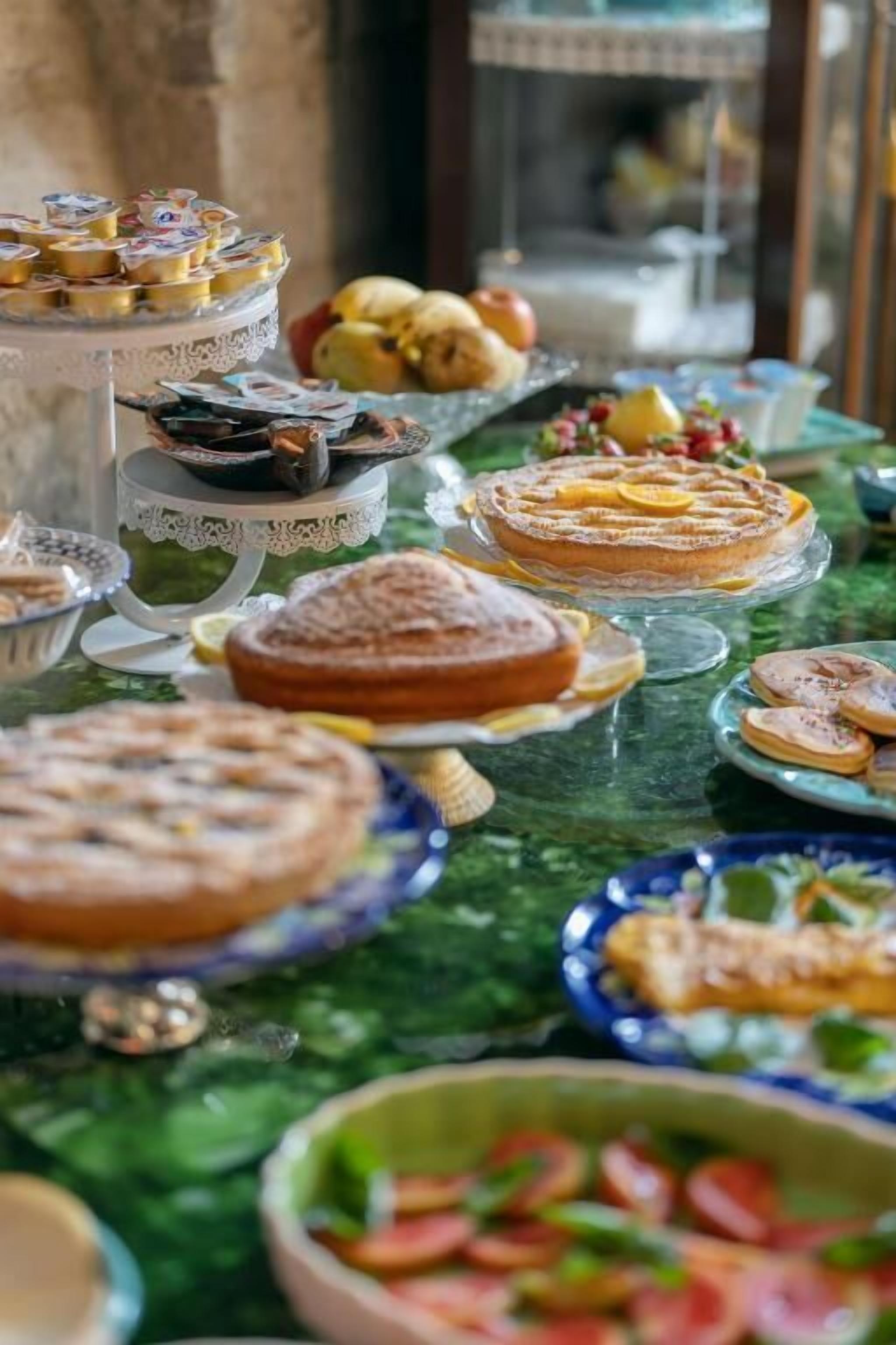 Una mesa con diversos postres y frutas, como pasteles y un frutero.