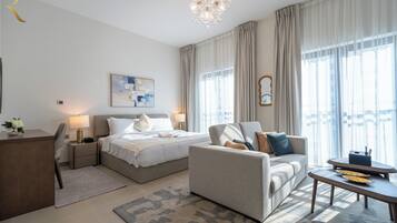 Una habitación de hotel moderna con cama, sofá, escritorio y un ventanal con cortinas.