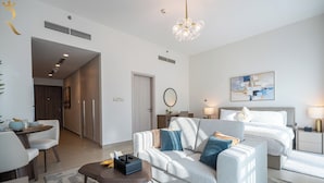 A modern hotel room with a sofa, a bed, a desk, and a dining area. - Yas Golf Collection Apartments (Abu Dhabi)