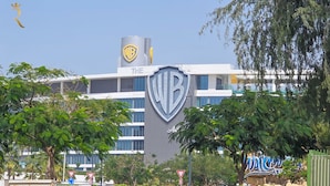 A building with a large Warner Bros. logo, surrounded by trees and palm trees. - Yas Golf Collection Apartments (Abu Dhabi)