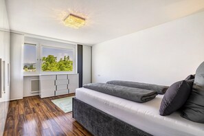 A bedroom with a bed, a radiator, a window, and a view of greenery. - Apartment 'Cozy' with Mountain View, Private Terrace and Wi-Fi (Dornbirn)