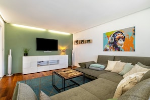 A modern living room with a sofa, coffee table, and a flat-screen TV mounted on the wall. - Apartment 'Cozy' with Mountain View, Private Terrace and Wi-Fi (Dornbirn)