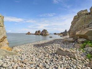A rocky beach with large boulders and a calm sea. - 200 m direct sea access - Charming house 2 ppl (Penvénan)