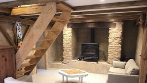 A cozy room with a stone fireplace, a wooden staircase, and a white sofa.