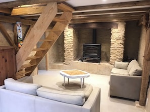 A cozy room with a stone fireplace, a wooden staircase, and a white sofa. - La p'tite maison ... 3 chb 85mm2 (Sainte-Mondane)