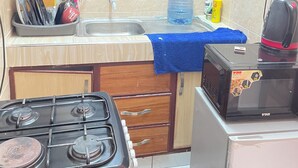 Cozinha com fogão a gás, micro-ondas, pia e janela com grades.