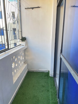 A small balcony with artificial grass, a potted plant, and a metal railing. - Silversands Studio Apartment in Bamburi, Mombasa (Mombasa)