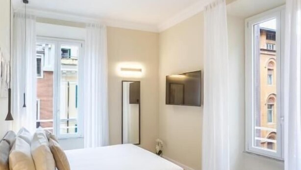 Une chambre à coucher moderne avec un lit, une table de chevet et une vue sur l’extérieur.