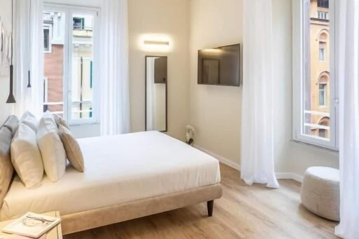 A modern bedroom with a bed, bedside table, and a view of the outside.