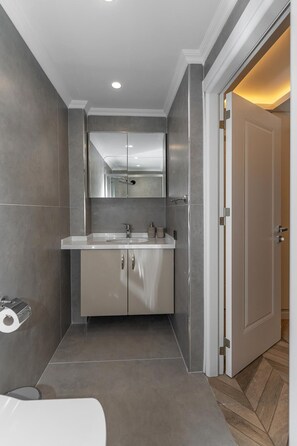 Een moderne badkamer met een grote spiegel, twee wastafels en een toilet.