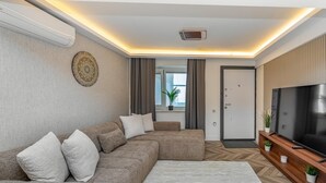 A modern living room with a sectional sofa, a flat-screen TV, and a herringbone-patterned floor. - Modern Sea View Stay Near Istanbul Airport (İstanbul)