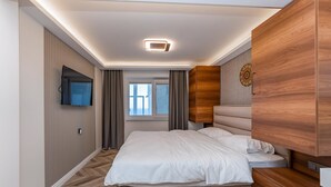 A bedroom with a bed, a TV mounted on the wall, a window with curtains, and a wooden wardrobe. - Modern Sea View Stay Near Istanbul Airport (İstanbul)