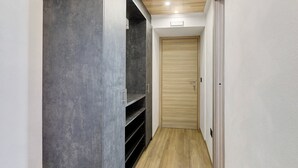A narrow hallway with a grey wall, a wooden door, and a light wooden floor. - Apartment "Cima Piazzi" – Comfort, Relaxation, and Nature between Bormio and Livigno (Semogo)