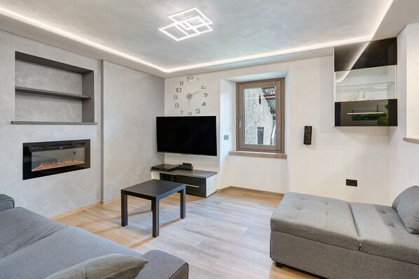 Un salon moderne avec un téléviseur à écran plat, une cheminée, un canapé et une petite table.