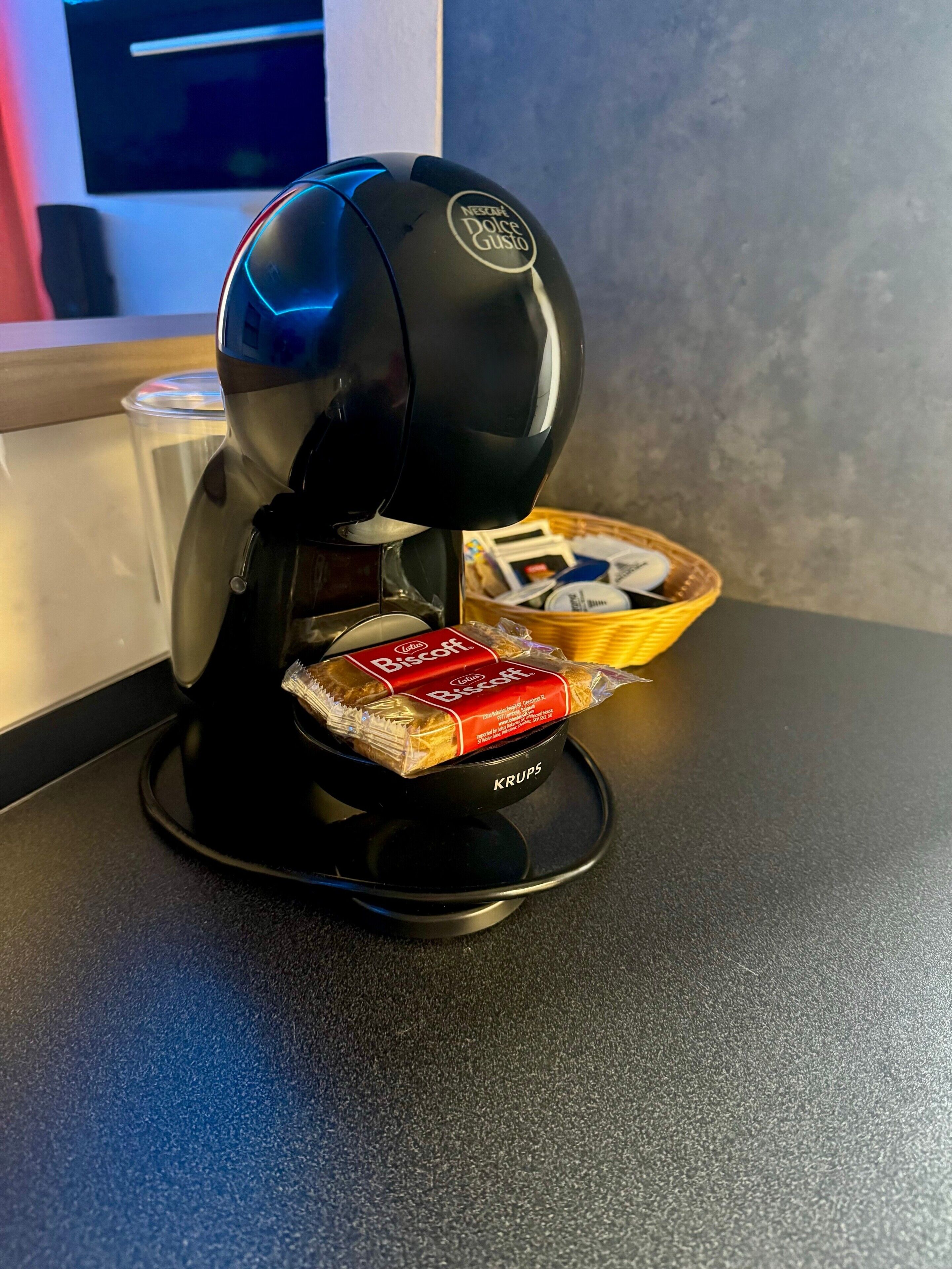 A coffee machine with a basket of biscotti and a box of biscotti on a countertop.