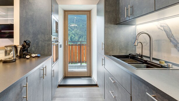 A modern kitchen with a built-in oven, a stainless steel sink, and a view through a glass door to a balcony. - Apartment "Cima Piazzi" – Comfort, Relaxation, and Nature between Bormio and Livigno (Semogo)