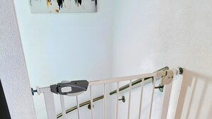 A white metal railing, a tiled floor, and a white wall with a light switch. - Apartment 'City High Mountain' with Private Terrace, Private Garden and Wi-Fi (Brunnthal)