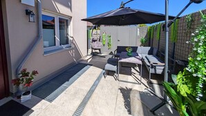 A patio with outdoor furniture, a hanging chair, and a table with a vase of flowers. - Apartment 'City High Mountain' with Private Terrace, Private Garden and Wi-Fi (Brunnthal)