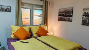 A bed with yellow and orange pillows, a purple bedspread, and a yellow blanket. - Apartment 'City High Mountain' with Private Terrace, Private Garden and Wi-Fi (Brunnthal)