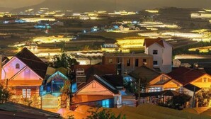 Un pueblo rural al atardecer con casas e iluminados campos.