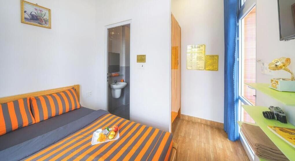 A hotel room with a bed, a small table with a tray of food, a window with curtains, and a bathroom visible through an open door.