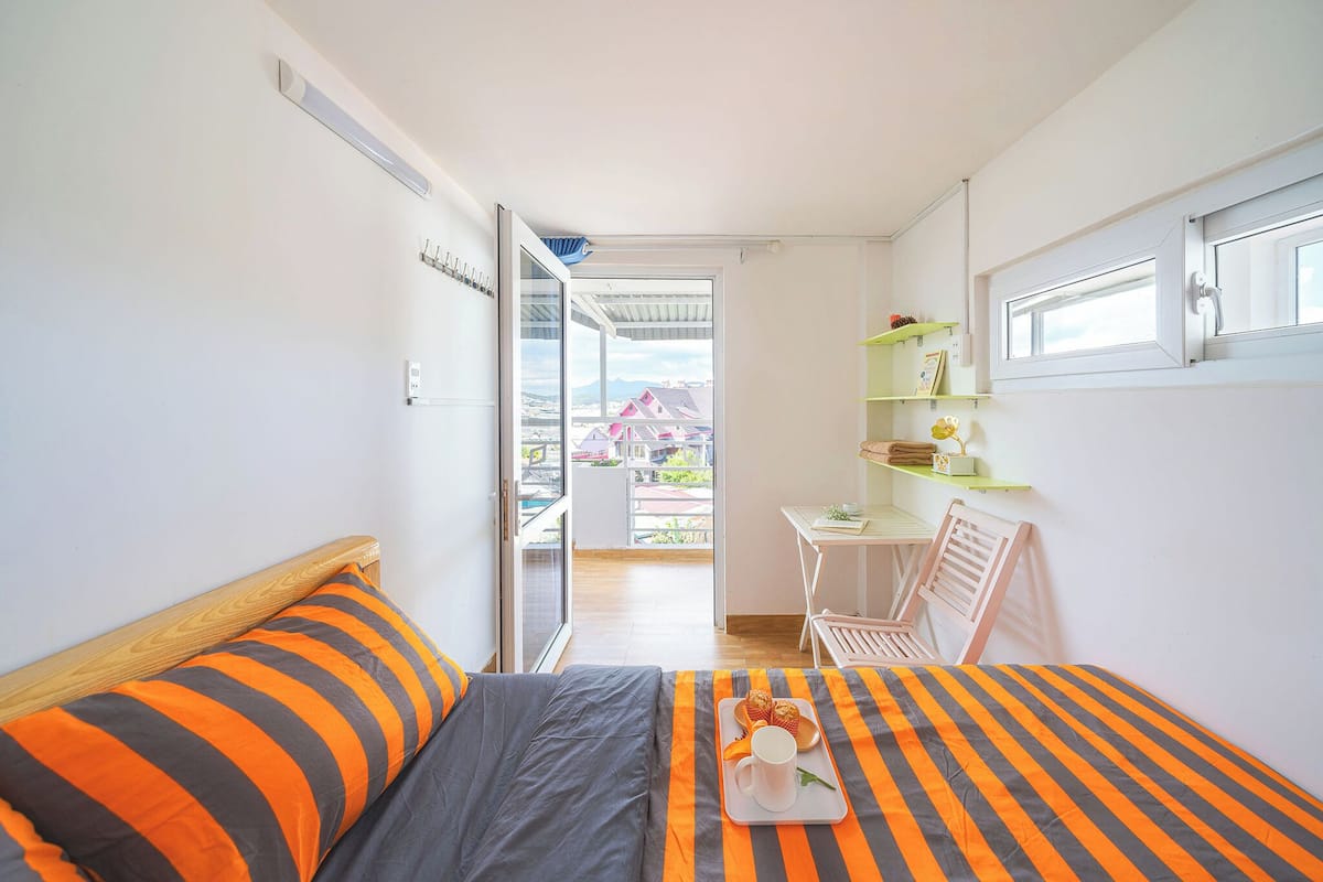 Un dormitorio con una cama, una bandeja con alimentos para el desayuno, un escritorio y una silla.