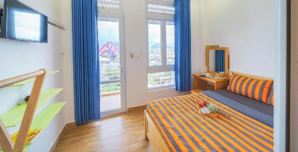 Une chambre à coucher avec un lit, un bureau, une chaise, une fenêtre et une vue sur l’extérieur.