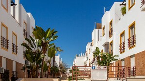 Un patio con edificios blancos, un camino central y palmeras.