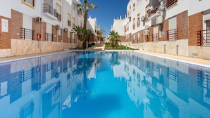 Una piscina con superficie de agua azul cristalina, rodeada de edificios de varios pisos con balcones y fachadas de ladrillo.