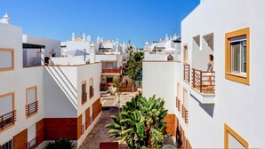 Una calle estrecha flanqueada por edificios con balcones, un camino central y una persona en un balcón.