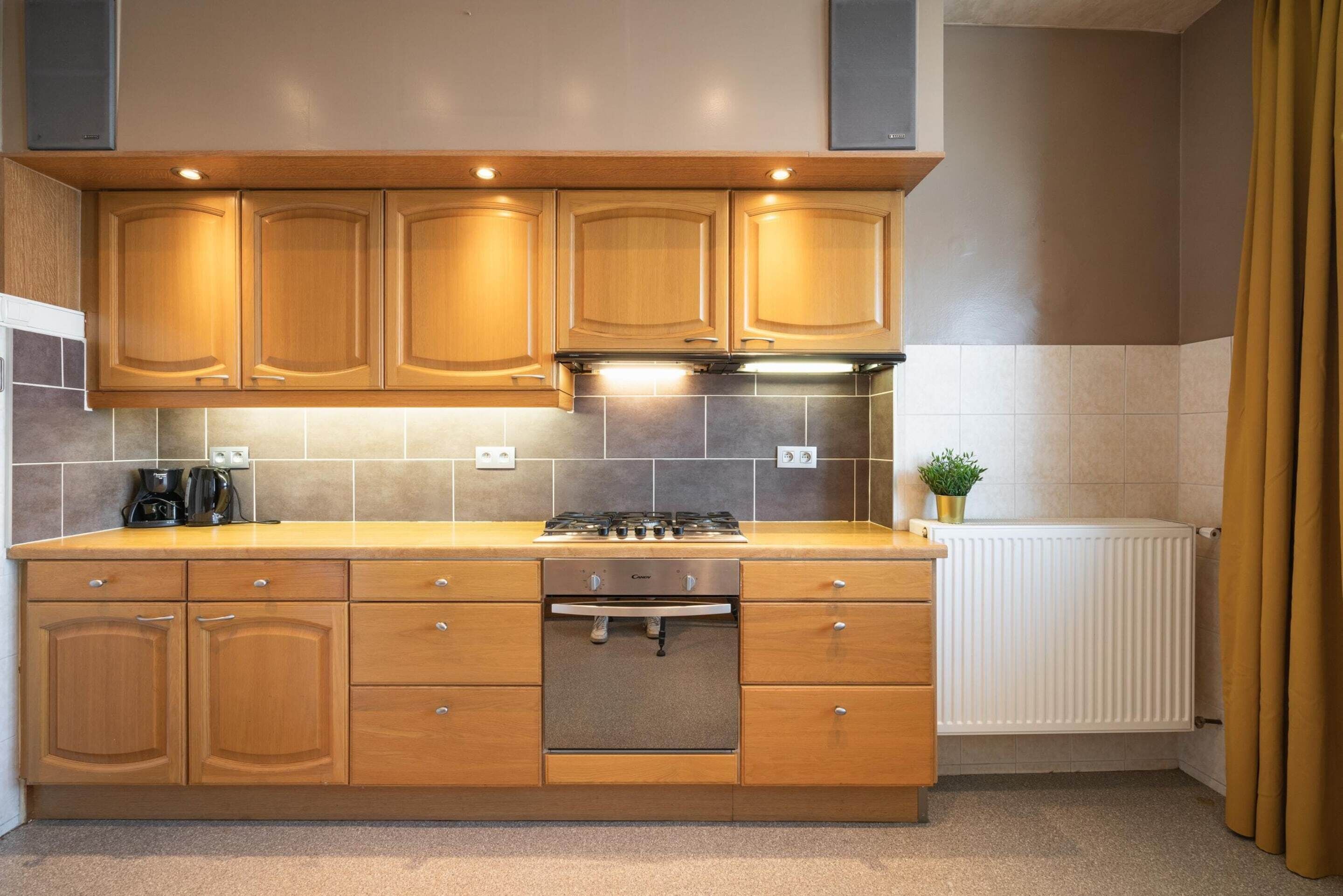 A kitchen with wooden cabinets, a built-in oven, and a tiled backsplash.