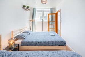 A bedroom with a bed, bedside table, lamp, and a window with curtains. - Large Antwerp City Center Apartments2bbkns (Antwerp)
