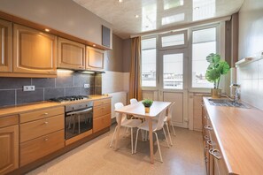A modern kitchen with wooden cabinets, a gas stove, and a dining area with a table and chairs.
