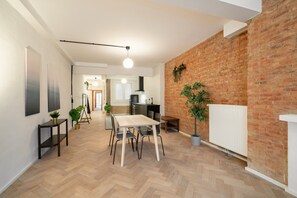 Een moderne keuken met een bakstenen muur, houten vloer en een eethoek met een tafel en stoelen.