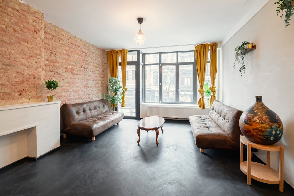 A living room with a brick wall, two sofas, a coffee table, and a large vase.