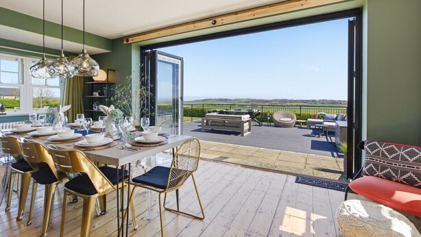 Ein Essbereich mit Tisch für sechs Personen, ein Balkon mit Sitzgelegenheit im Freien und Blick auf die Landschaft.