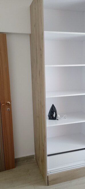 A room with a wooden wardrobe, a white shelf unit, and a door with a key lock. - Perfect 1-bedroom apartment with AC in peaceful Nairobi (Nairobi)