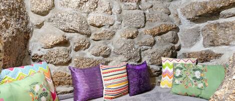 Un muro de piedra con un banco y almohadones coloridos.