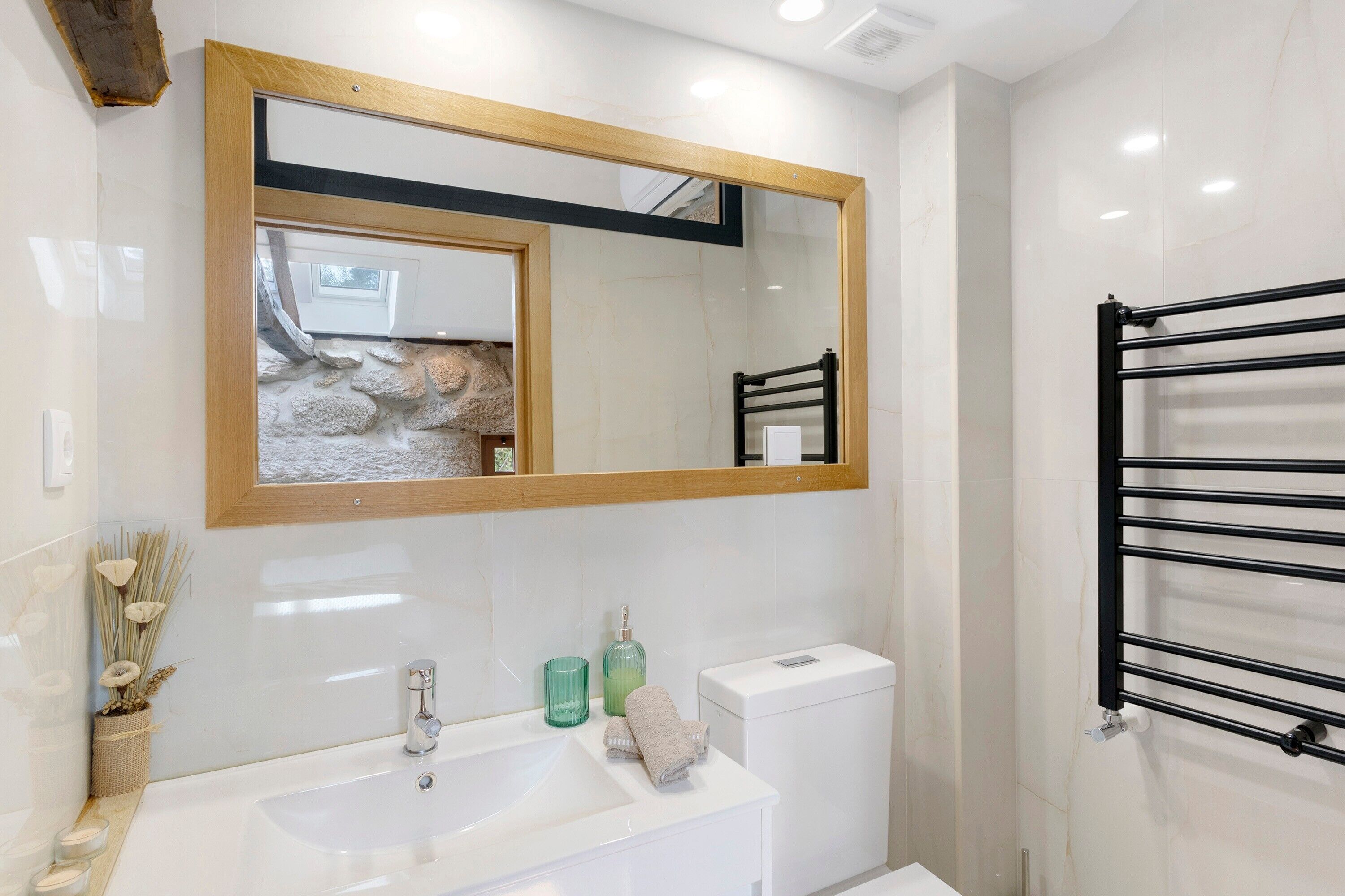 Casa de banho com lavatório branco, espelho e porta-toalhas.