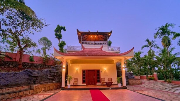 A traditional building with a tiled roof and a red carpet leading to the entrance. - Ushasree Wayanad Resort by VOYE HOMES (Sulthan Bathery)