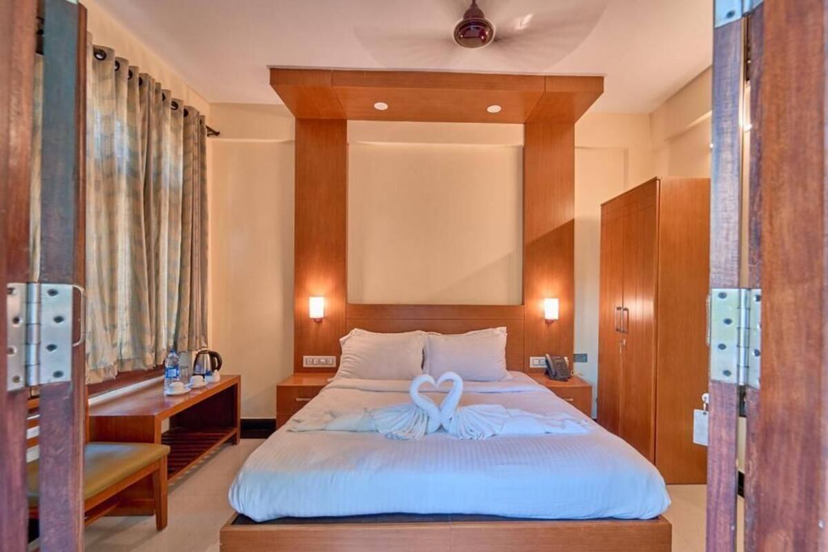 A hotel room with a bed, bedside tables, a wooden headboard, and a wardrobe.