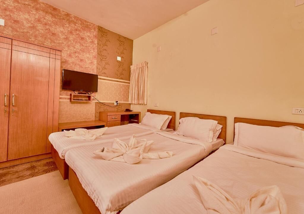 Ein Hotelzimmer mit zwei Betten, einem Fernseher, einem Kleiderschrank und einem Badezimmer mit Vorhang.