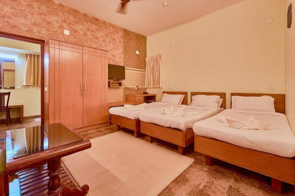 A hotel room with two beds, a wooden desk, a television, and a wardrobe.