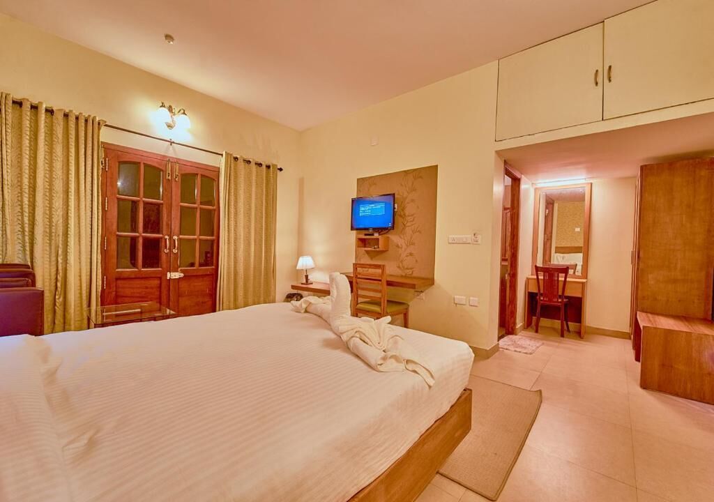 Een hotelkamer met een bed, een televisie, een bureau en een spiegel.